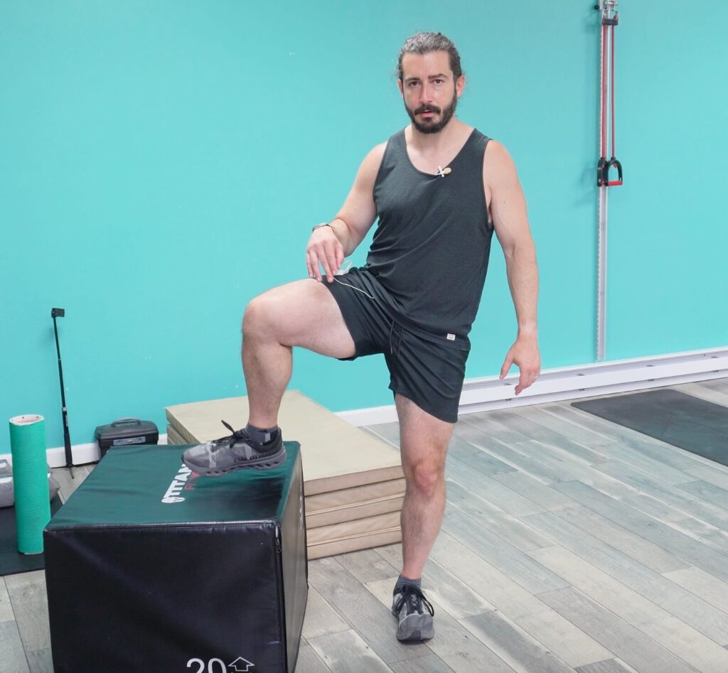 Dr. John gliding his right leg over a box for the standing hip cars exercise